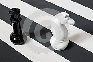 Chess pieces on a striped surface. the stripes are black and white. knight and queen