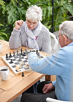 Chess, strategy and senior couple thinking while playing a board game in the backyard or bonding together. Mind, relax
