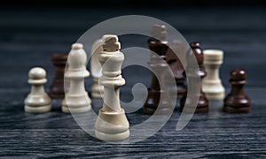 Chess white king and various chess pieces on a wooden background