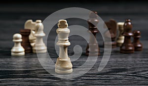 Chess white king and various chess pieces on a wooden background