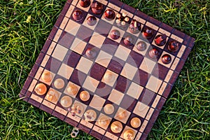 Chessboard and chess pieces on the grass in the garden