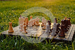 Chessboard and chess pieces on the grass in the garden