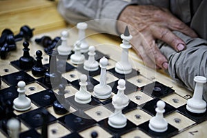 Chessboard with an elderly man sitting at it. Leisure for pensioners and older people. An unfinished chess game. Photo. Selective