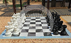 Chessboard with huge black and white chess figures for outdoor playing. Nice backgrounds