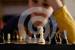 A chessboard with spaced figures, in the background a boy out of focus. Education concept, intellectual game