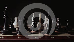 Chessboard with white and black chess pieces on black background