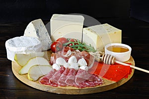 Chesse platte with different cheeses, meats on wooden board