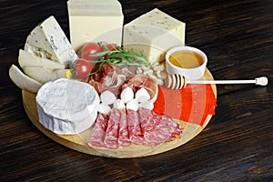 Chesse platte with different cheeses, meats on wooden board