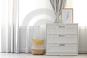 Chest of drawers near window with stylish curtains in living room. Interior design