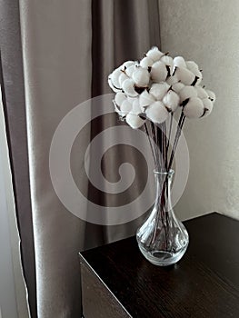 on the chest of drawers you will dig up there is a bouquet of white cotton flowers in a glass vase