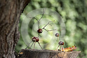 Chestnut animals on wooden stump, deer and female deer made of chestnuts, acorns and twigs, green background