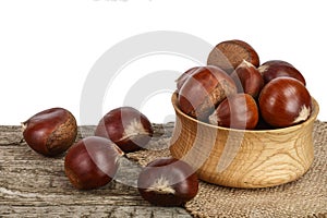 Chestnut in bowl on the old wooden table with white background