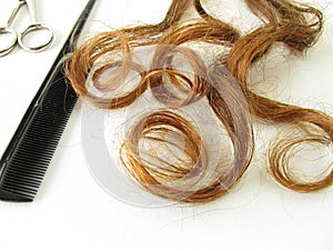 Chestnut-brown hair, scissors and comb