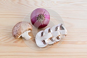 Chestnut mushrooms and red onion on wood