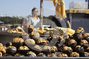 Chestnuts & x28;chestnut kebab& x29; close-up. Walking people blurred background. The seller withdrew on the counter