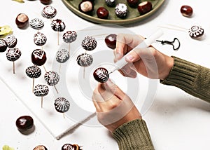 Chestnuts decorated with white acrylic painter. Creative crafts with natural material.