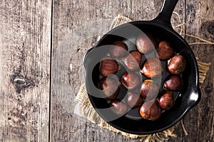 Chestnuts in iron pan on wooden table