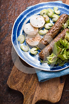 Chevanchichi with lettuce and daikon on a blue plate on the board