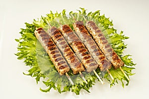 Chevapchichi, meat appetizer on a white background. Lettuce leaves complement the meat dish. Lula-Kebab. Selective focus