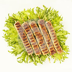 Chevapchichi, meat appetizer on a white background. Lettuce leaves complement the meat dish. Lula-Kebab. Selective focus