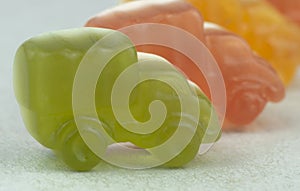 Chewing marmalade in the shape of racing cars on a light background close-up.Green, red, orange.