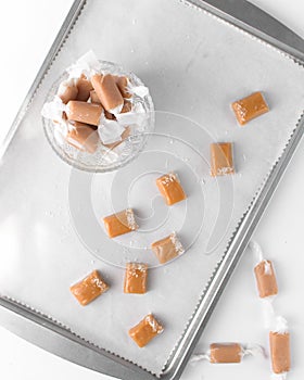 chewy caramels wrapped and unwrapped. Caramel candies in a small bowl