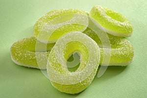 Chewy sweets and apple flavoured gummy candy concept with close up on sweet and sour green rings covered in granulated sugar