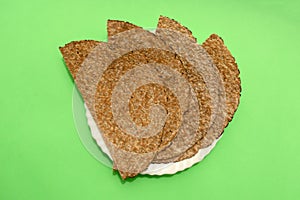 Chia flatbread in white plate on a green background. Flat lay, top view