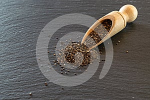 Chia healthy flax seed in wooden spoon. Pile superfood isolated on black food background. Vitamin snack breakfast, diet