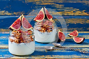 Chia milk pudding with granola and fresh figs in the glass jars on the blue wooden kitchen table. Detox superfoods breakfast