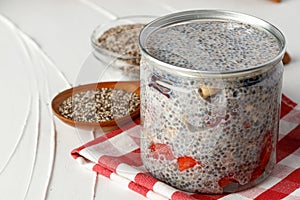 Chia pudding and raw chia seeds on white table