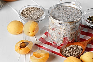 Chia pudding and raw chia seeds on white table