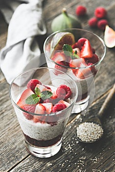 Chia pudding with red berries in glass on wooden table