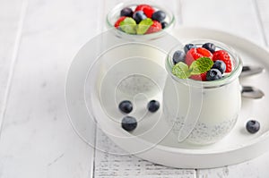 Chia seed pudding with fresh berries on a white wooden table.