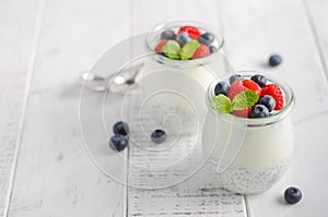 Chia seed pudding with fresh berries on a white wooden table.