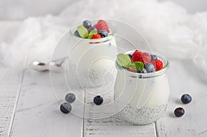 Chia seed pudding with fresh berries on a white wooden table.