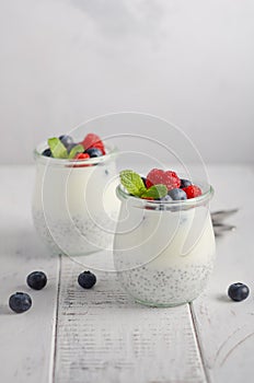 Chia seed pudding with fresh berries on a white wooden table.