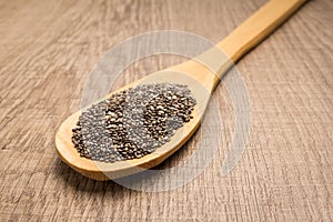 Chia Seed. Spoon and grains over wooden table.