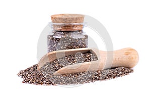 Chia seeds in glass jar and wooden spoon, isolated on white background. Healthy superfood. Closeup macro of small