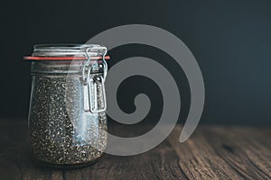 Chia seeds in glass weck jar on wooden table against dark background
