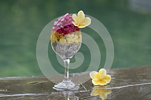 Chia seeds pudding with red dragon fruit and white yogurt in a glass for breakfast on the background of the swimming pool water. photo