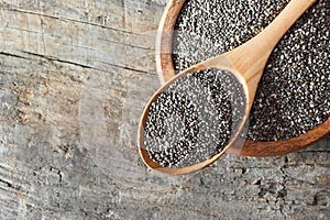 Chia seeds  Salvia Hispanica  in wooden spoon and bowl on wooden rustic background