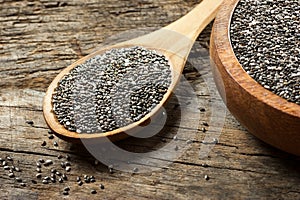 Chia seeds  Salvia Hispanica  in wooden spoon and bowl on wooden rustic background