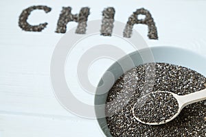 Chia seeds in a wooden spoon in a bowl on the table close-up.
