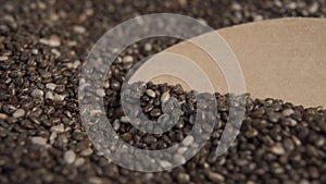 Chia seeds in a wooden spoon and in a heap. A spoon grabs the seeds in close-up.