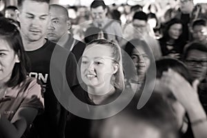 Gritty defocused effect of faces of crowd of people in night street scene illuminated