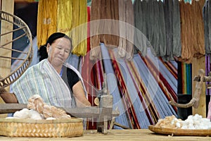 woman spinning cotton into thread with traditional wheel