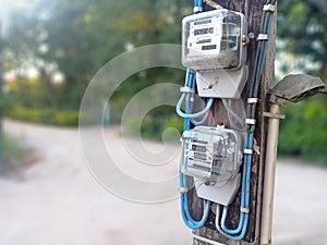 Chiangrai,Thailand, October 2020: 2 electric meters power with the pole next to street in a countryside village isolated on