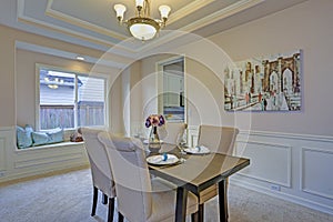 Chic dining room accented with wall panel mouldings and tray ceiling.