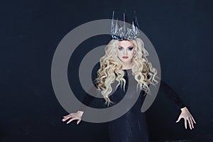 Chic Gothic Queen from a dark fairy tale. Young blonde woman in black with steel crown on her head